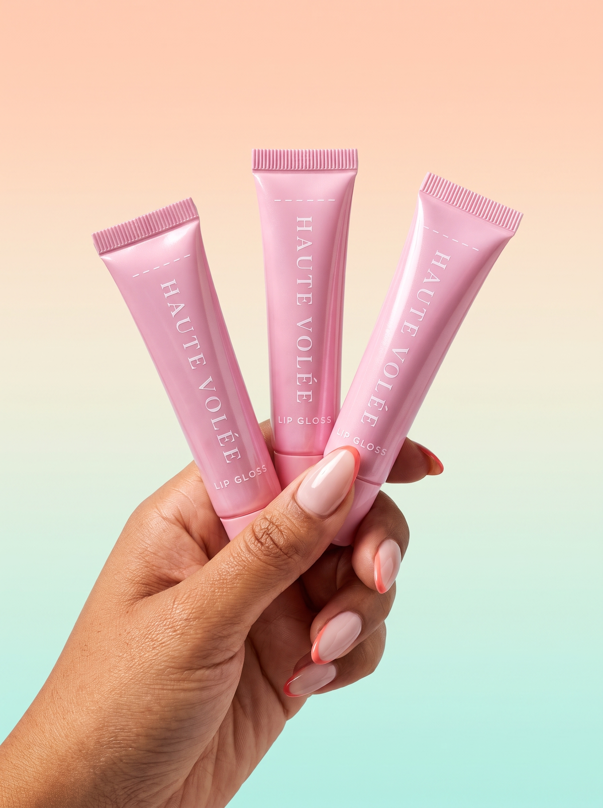 Drei rosa HAUTE VOLÉE Lipgloss-Tuben in der Hand vor Pastell-Hintergrund (KI-generiertes Bild)