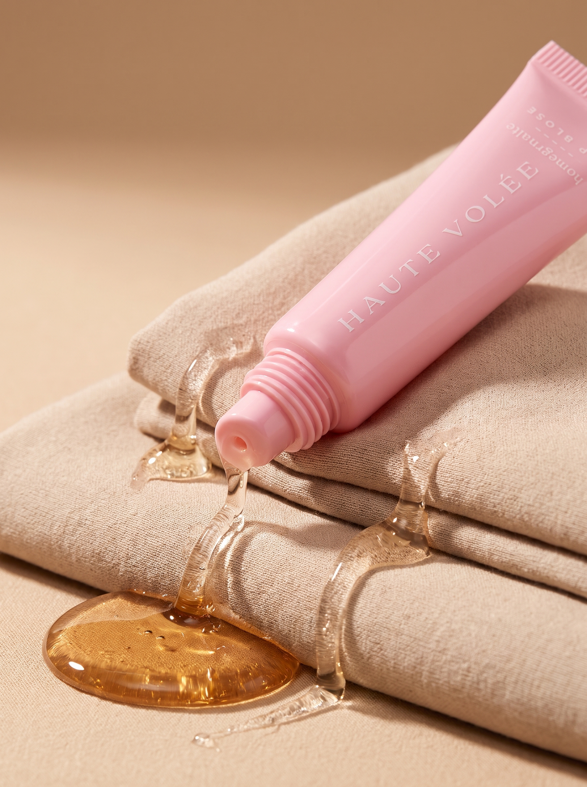 Lip Gloss Argan Oil: rosa Tube mit Kettenanhänger auf beigem Stoff (KI-generiertes Bild)