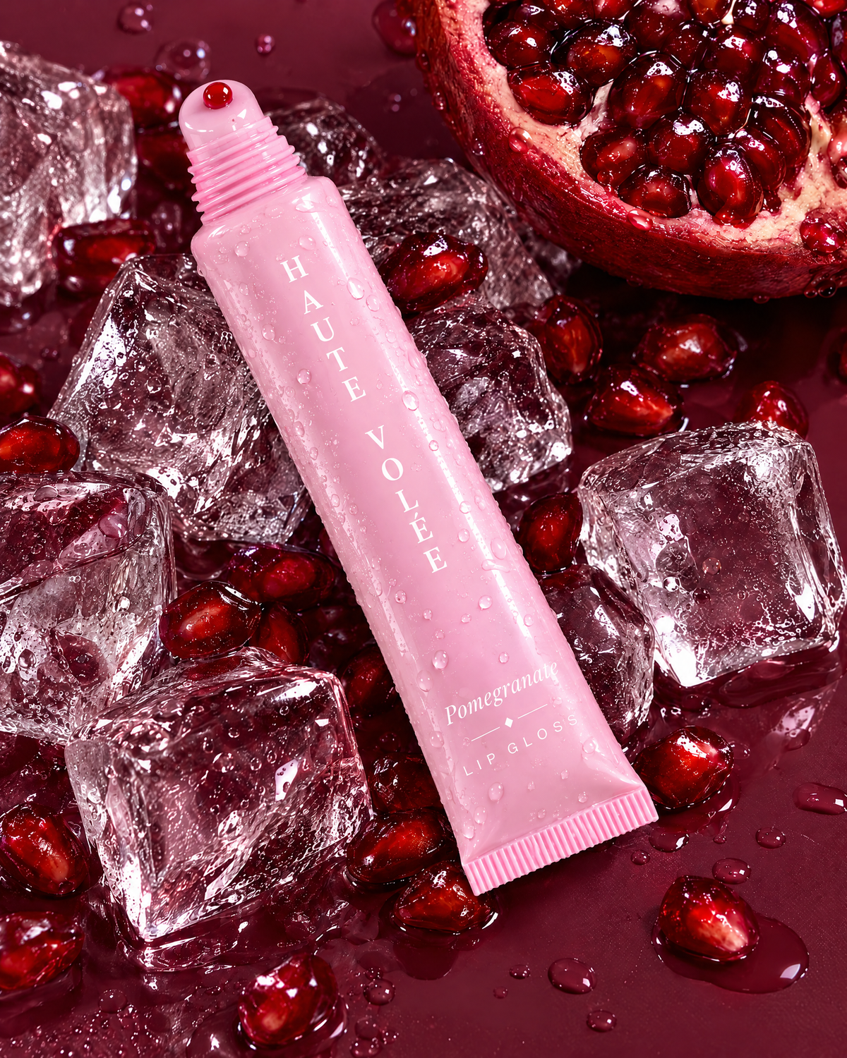 Lip Gloss Pomegranate: rosa Tube zwischen Granatapfel und Eiswürfeln (KI-generiertes Bild)